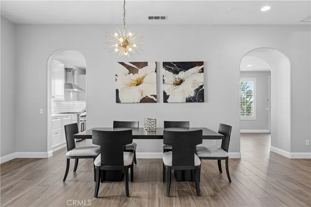 a dining room with wooden floor a chandelier a wooden table and chairs