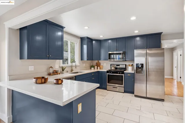a kitchen with stainless steel appliances granite countertop a sink a stove a refrigerator a washer and dryer