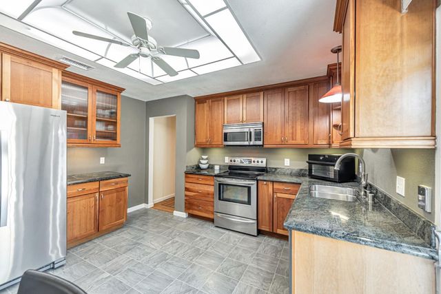 a kitchen with stainless steel appliances granite countertop a sink window and cabinets