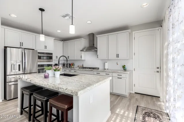 a kitchen with stainless steel appliances granite countertop a stove a sink dishwasher and a refrigerator with wooden floor