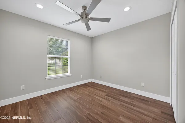 an empty room with wooden floor and windows