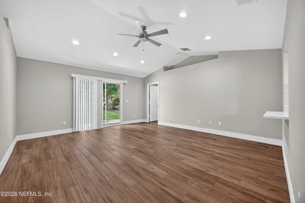 an empty room with wooden floor and windows
