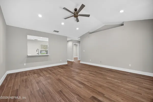 an empty room with wooden floor and a ceiling fan
