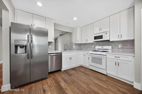 a kitchen with white cabinets stainless steel appliances and a counter space