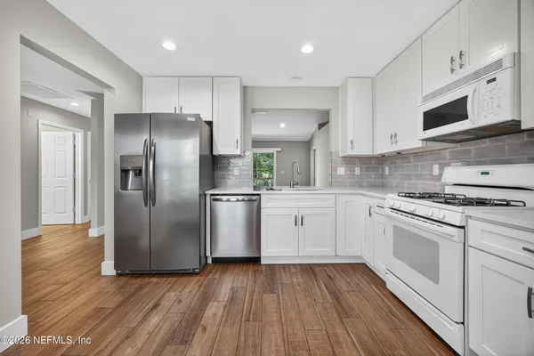 a kitchen with cabinets stainless steel appliances and wooden floor
