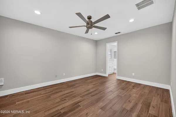 an empty room with wooden floor and a ceiling fan