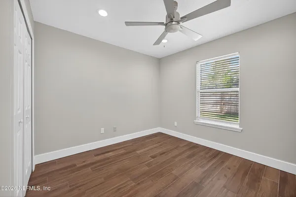a view of an empty room with wooden floor and a window