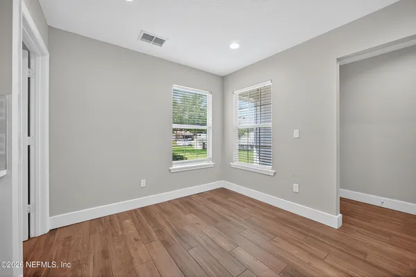 an empty room with wooden floor and windows