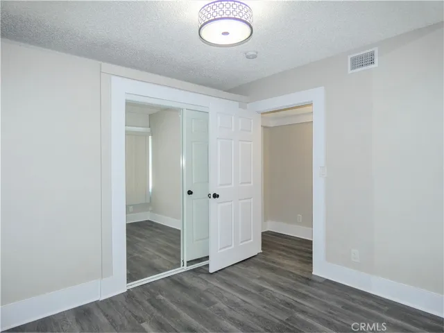 an empty room with wooden floor and mirror