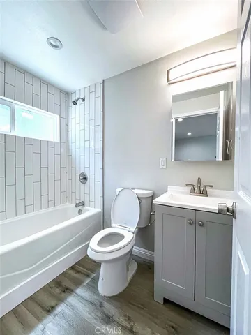 a bathroom with a toilet a sink a mirror a bathtub and vanity