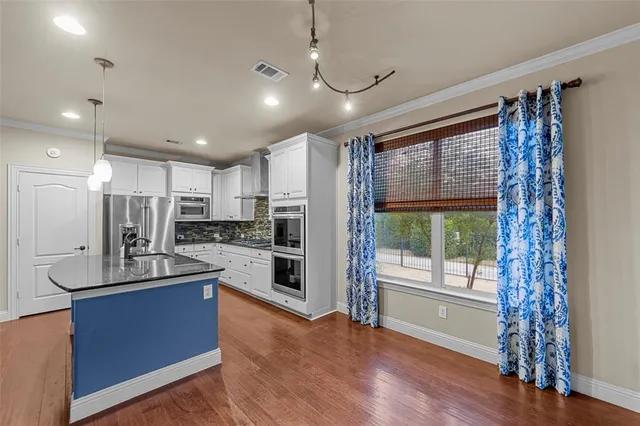 a kitchen with kitchen island a counter top space a sink stainless steel appliances and cabinets