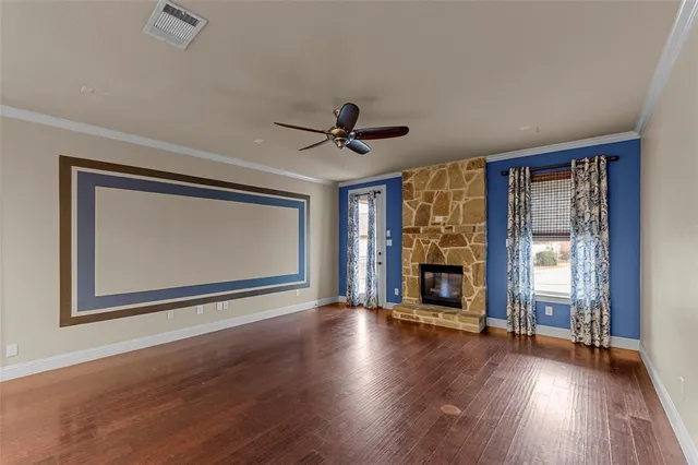 a view of an empty room with wooden floor fireplace and a window