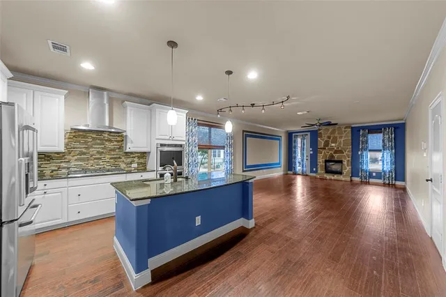 a kitchen with kitchen island granite countertop a stove top oven a sink a counter space and cabinets