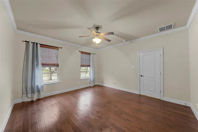 a view of an empty room with window and wooden floor