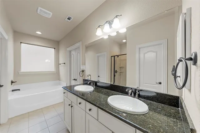 a bathroom with a granite countertop sink a mirror a vanity and a bathtub