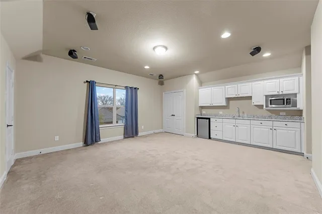 a view of a kitchen with a sink and dishwasher a refrigerator with white cabinets