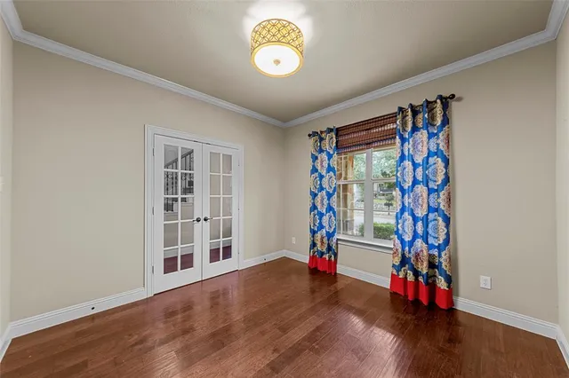 a view of an empty room with a window and hardwood floor