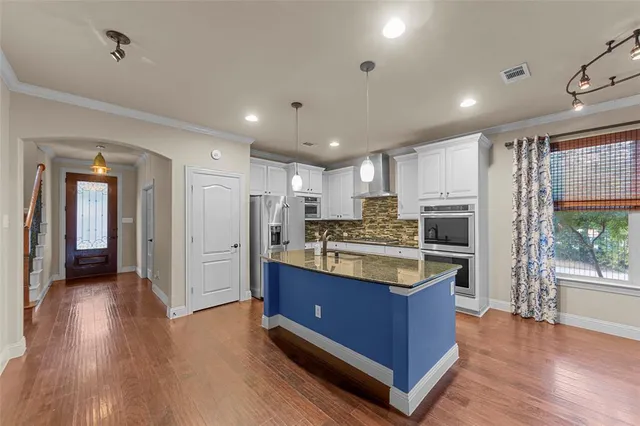 a kitchen with kitchen island granite countertop wooden floors and stainless steel appliances