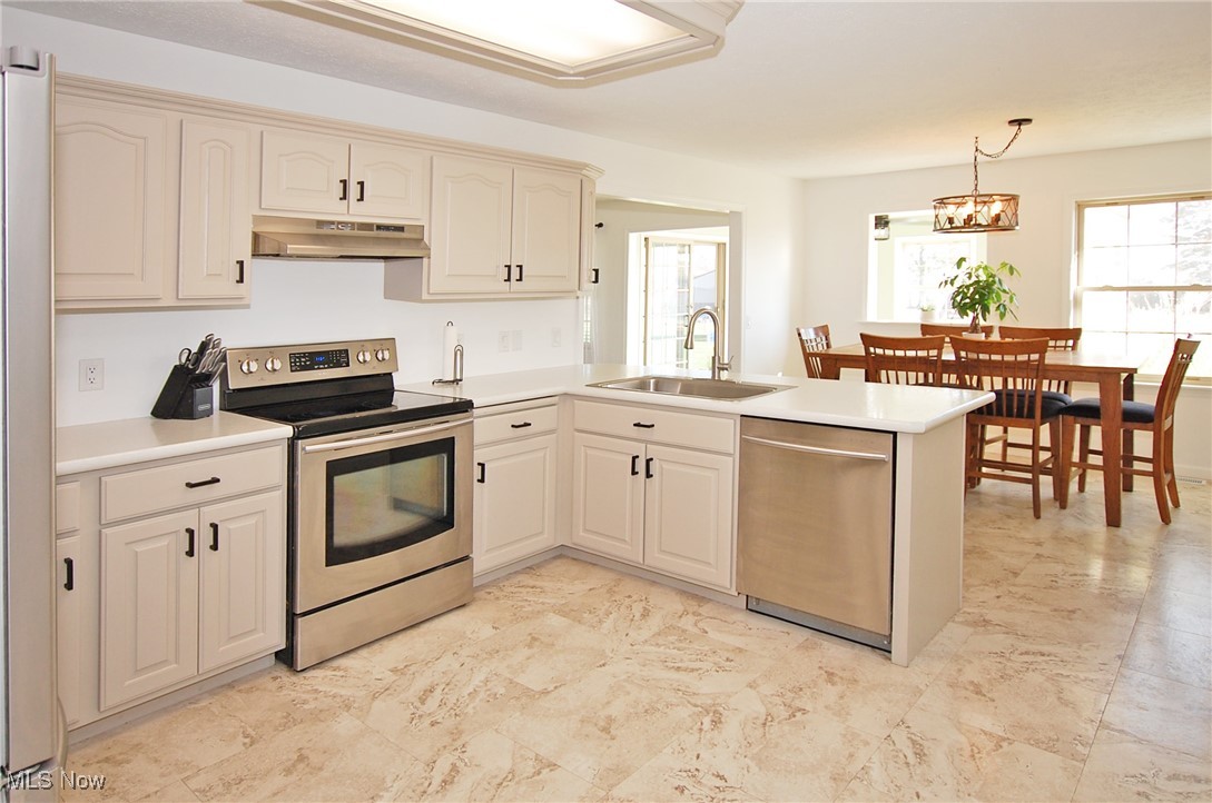 26875 W Road Wellington, OH 44090 - Photo 4 of 26 Kitchen featuring hanging light fixtures, kitchen peninsula, stainless steel appliances, sink, and a chandelier