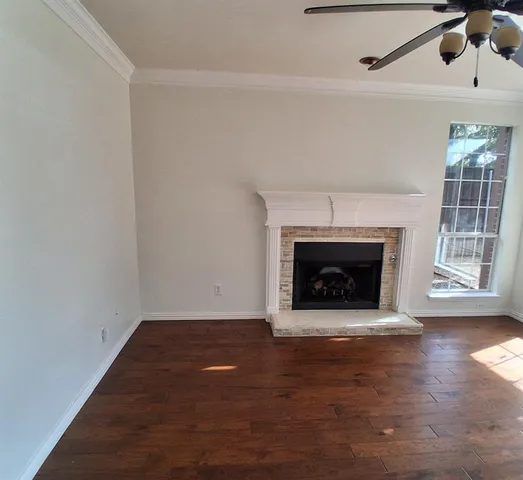 a view of an empty room with wooden floor fireplace and a window