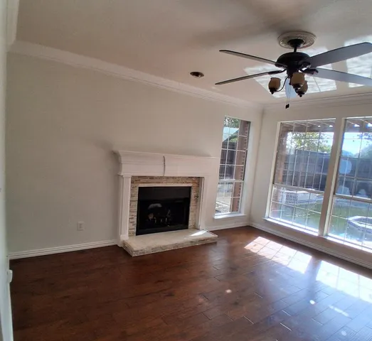 a view of an empty room with wooden floor fireplace and a window