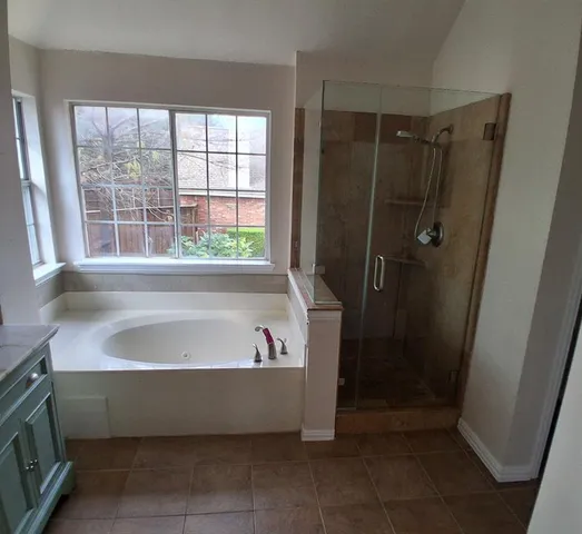 a spacious bathroom with a granite countertop double vanity sink a large mirror and a bathtub