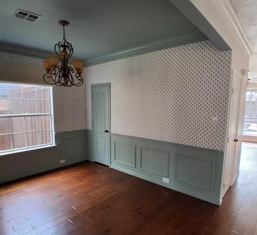 an empty room with wooden floor chandelier and windows
