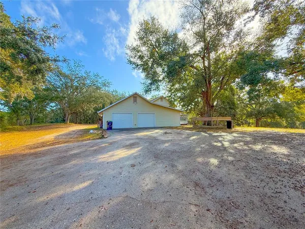 a view of the house with a yard and large trees