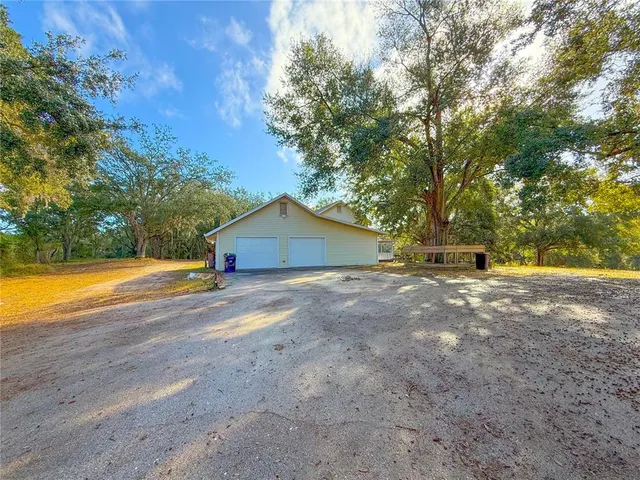 a view of the house with a yard and large trees