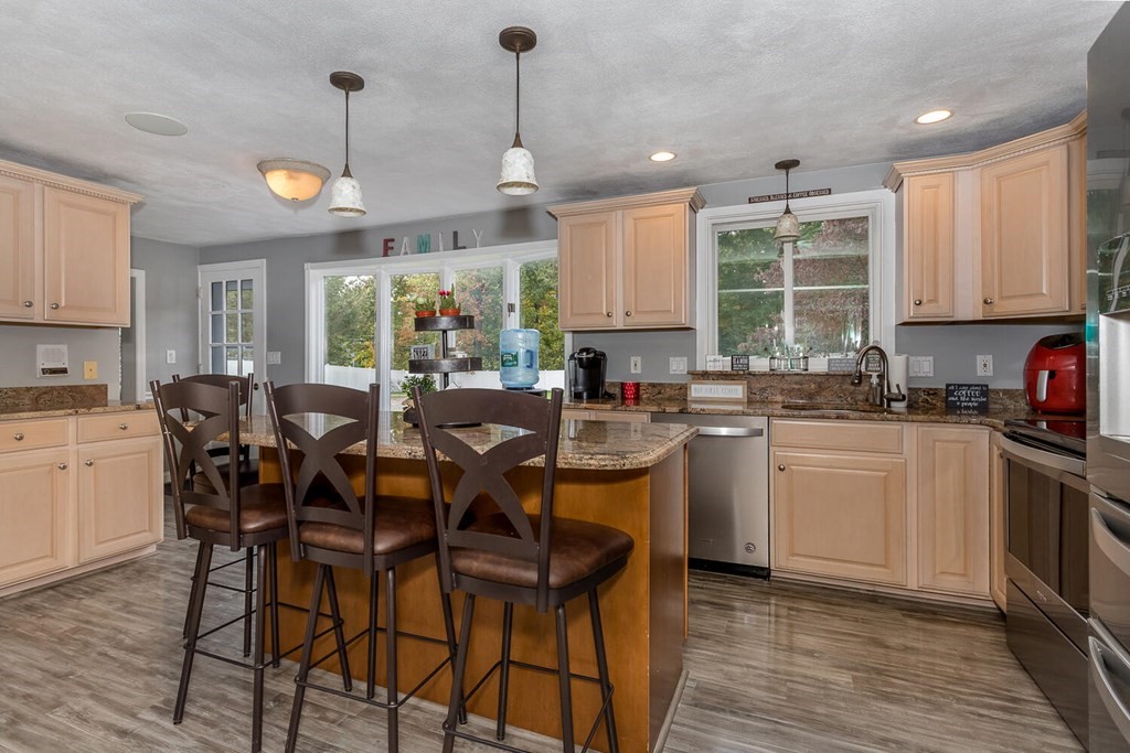34 Fairview Road Canton, MA 02021 - Photo 6 of 23 a kitchen with stainless steel appliances kitchen island granite countertop a stove a refrigerator a sink a dining table and chairs with wooden floor