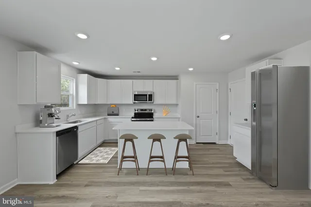 a kitchen with a sink a stove a refrigerator and white cabinets with wooden floor