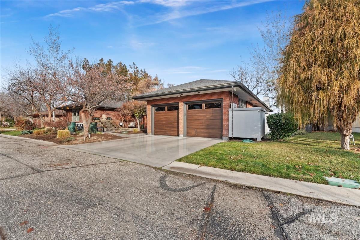 View of home's exterior with brick siding, concrete driveway, a lawn, and a garage