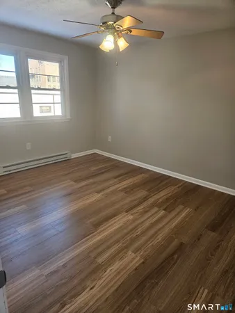 an empty room with wooden floor fan and windows