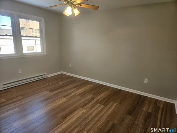 a view of an empty room with wooden floor and a window