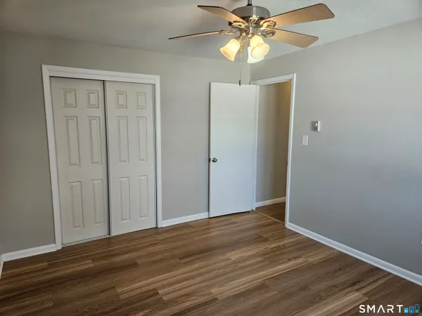 wooden floor in an empty room with a chandelier fan