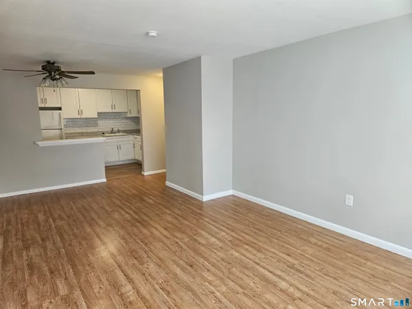 a view of kitchen and empty room with wooden floor
