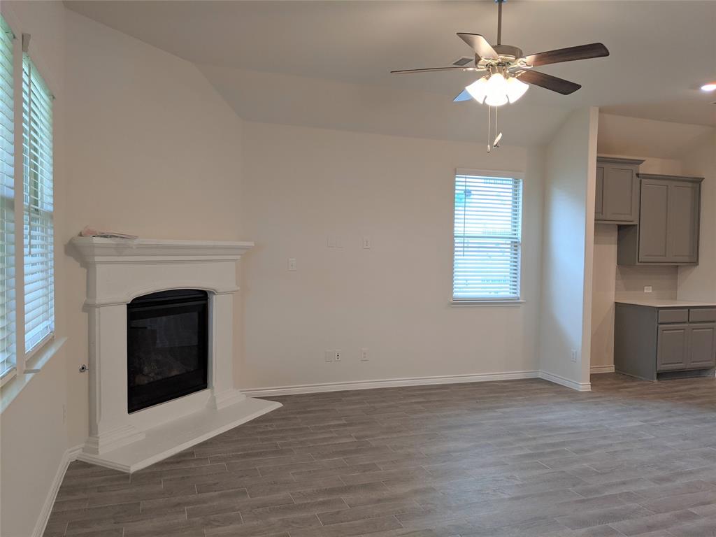 3024 Meredith Lane Forney, TX 75126 - Photo 16 of 22 a view of a livingroom with a fireplace a ceiling fan and windows