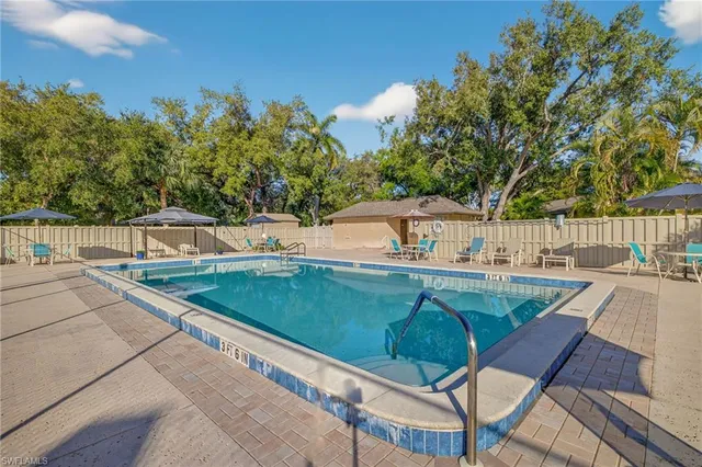 a sign of golf club on a wall under a large tree