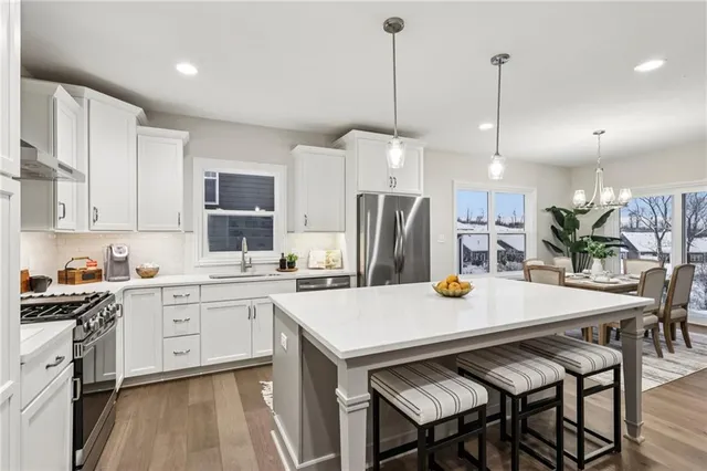 a kitchen with stainless steel appliances kitchen island a table chairs and a refrigerator