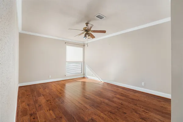 an empty room with wooden floor ceiling fan and windows