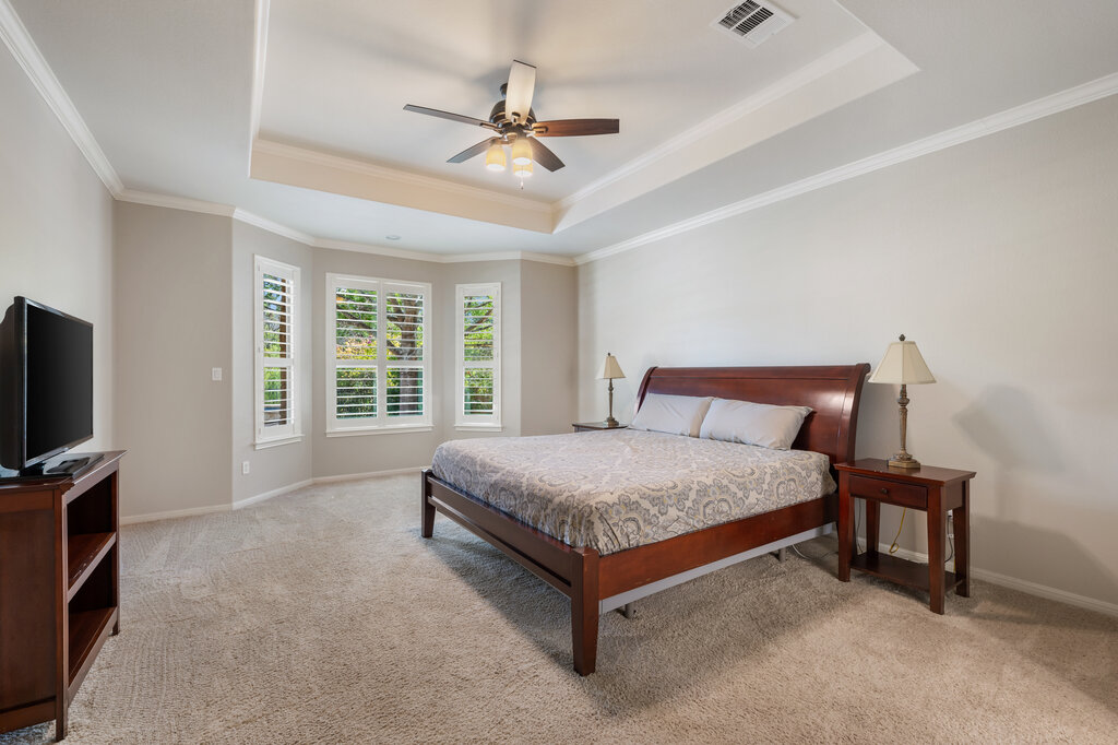 12801 Little Dipper Path Austin, TX 78732 - Photo 19 of 29 a spacious bedroom with a bed and a flat tv screen on wall