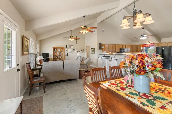 a living room with furniture kitchen view and a chandelier