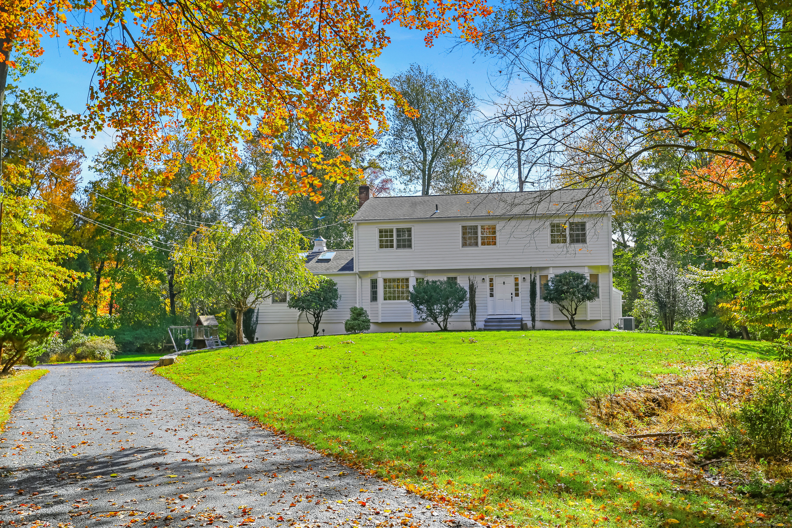 a view of a house next to a big yard and large trees