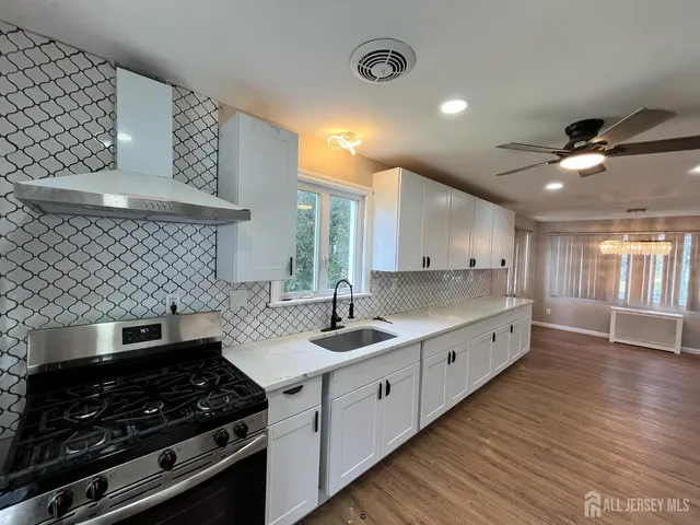 a kitchen with stainless steel appliances a stove a sink and wooden floor