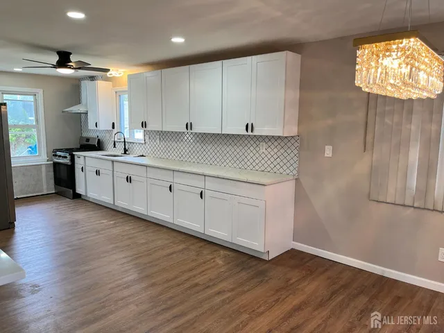 a large white kitchen with wooden floors and white stainless steel appliances