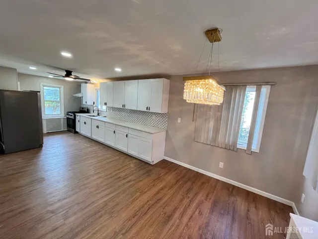 a large kitchen with stainless steel appliances a large counter top a wooden floors and a large window