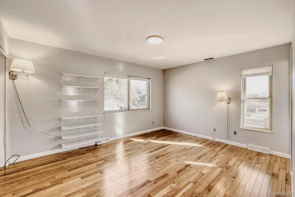 a view of empty room with wooden floor and fan