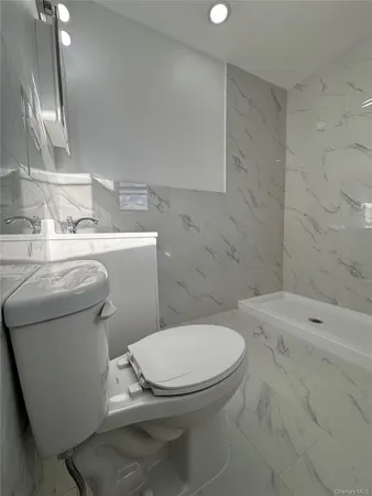a white toilet sitting next to a bathroom sink and vanity