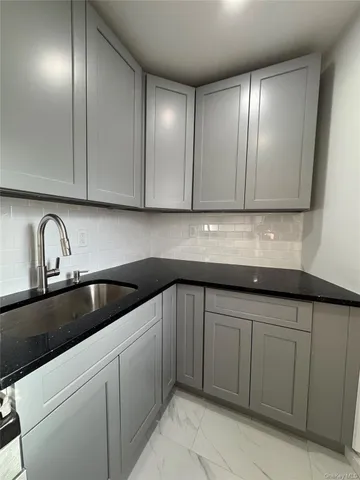 a kitchen with granite countertop white cabinets and sink