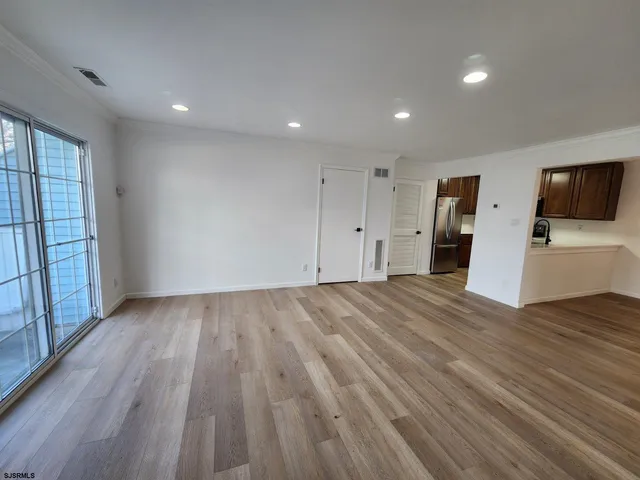 a view of empty room with wooden floor and window